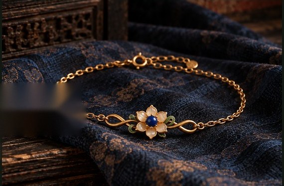 A fine gold chain bracelet set with two white lotus flowers, lying on indigo silk.